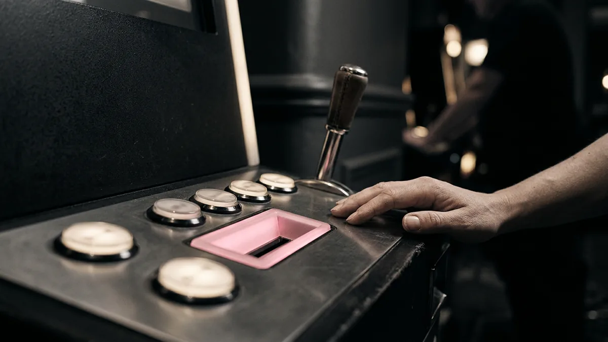 Upplysta knappar och spak på en spelautomat i en dämpad casinomiljö